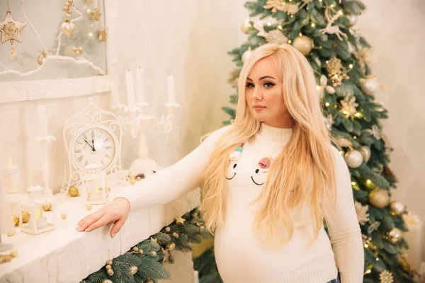 Schöne schwangere Frau legt ihre Hand auf ihren Bauch. Weihnachtsbaum. frohes neues Jahr — Stockfoto