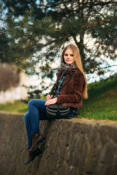 Активна молода дівчина сидить на набережній. Блондинка і коричневий піджак. Весна — стокове фото