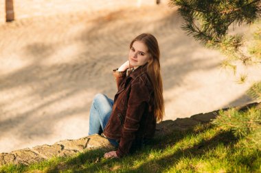 Attrective genç kız tarafından setin oturur. Sarı saçlı ve kahverengi ceket. Bahar