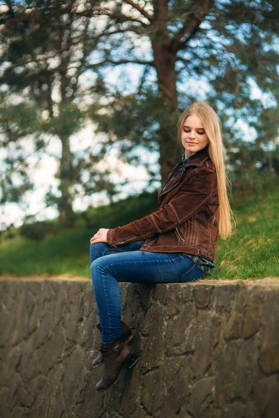 Fiatal lány ül a partra a Attrective. Szőke haj, barna kabátot. Tavaszi — Stock Fotó