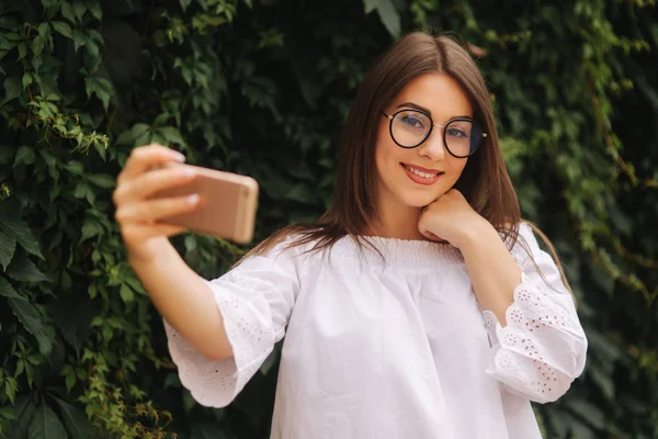 Joven mujer alegre viendo vídeo divertido en el teléfono inteligente mientras descansa al aire libre — Foto de Stock