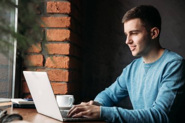 Bir kafede dizüstü bilgisayar ile genç programcı pencerenin oturur