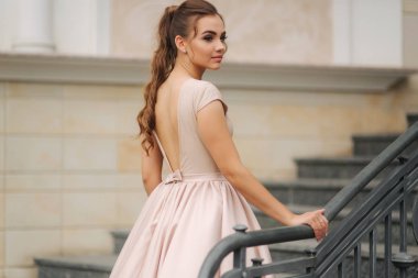 Otel tarafından merdivenlerde zarif esmer stand. Abiye moda modeli