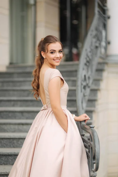 Elegante morena em pé nas escadas ao lado do hotel. Modelo de moda em vestido de noite — Fotografia de Stock