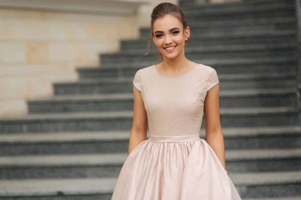 Die elegante Brünette steht auf der Treppe neben dem Hotel. Mode-Model im Abendkleid — Stockfoto