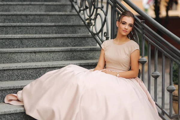 Fashion model sits on the stairs by the hotel. Beautiful lady with modern hairstyle — Stock Photo, Image