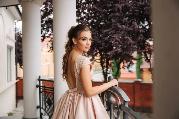 Молода модель з великою вечірньою сукнею стоїть біля ресторану. Брюнетка дівчина має красивий стиль волосся і макіяж — стокове фото