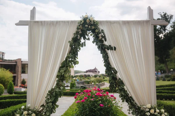 Hochzeitsdekoration unter freiem Himmel. Blumenschmuck eines schönen weißen Bogens. schöner Blick auf die Bäume — Stockfoto