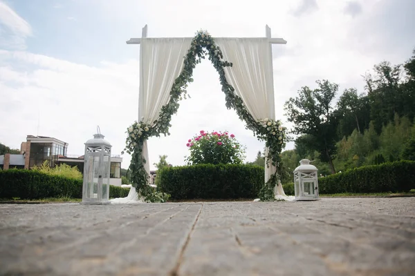 Weddind decoration on open air. Floral decor of a beautiful white arch. Beautiful beckground view of trees — Stock Photo, Image