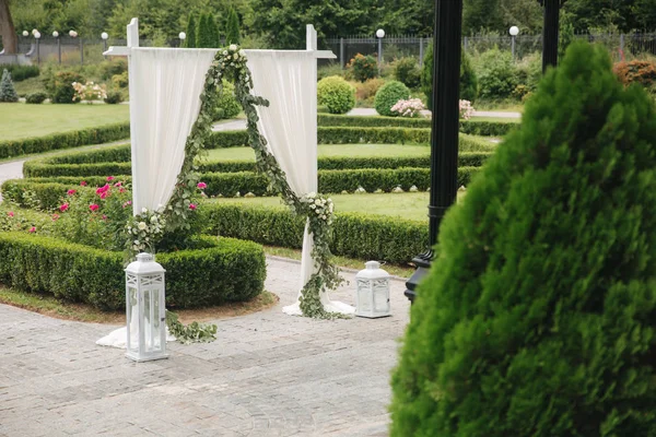 Weddind decoration on open air. Floral decor of a beautiful white arch. Beautiful beckground view of trees — Stock Photo, Image