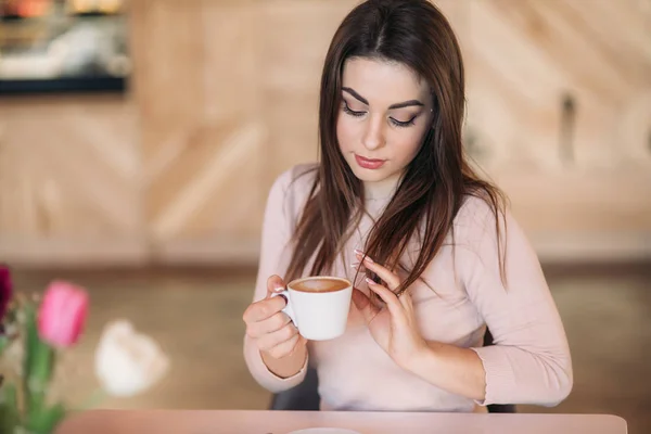 Gyönyörű lány ül a kávézóban, és iszik cappuccino — Stock Fotó