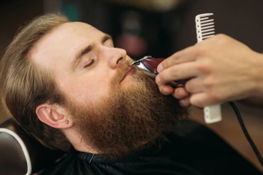 Sakallı adam bir saç kesimi saç kesme makineleri ile sahip