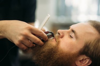 Sakallı adam bir saç kesimi saç kesme makineleri ile sahip