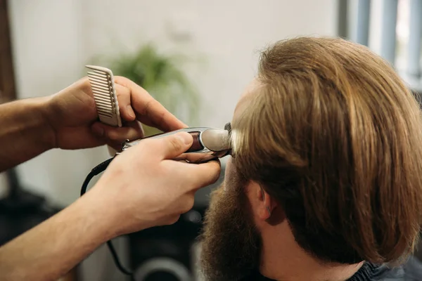 A kezében a fiatal fodrász fodrász hogy vonzó szakállas férfi fodrászat — Stock Fotó