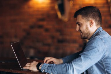 Bir kafede bir dizüstü bilgisayar üzerinde çalışan genç programcı