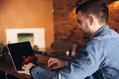 Bir kafede bir dizüstü bilgisayar üzerinde çalışan genç programcı