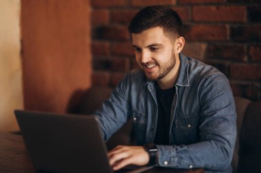 Bir kafede bir dizüstü bilgisayar üzerinde çalışan genç programcı