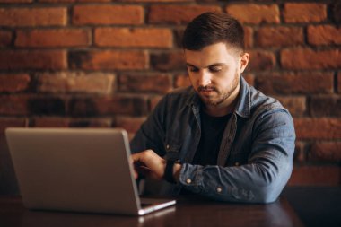 Bir kafede bir dizüstü bilgisayar üzerinde çalışan genç programcı