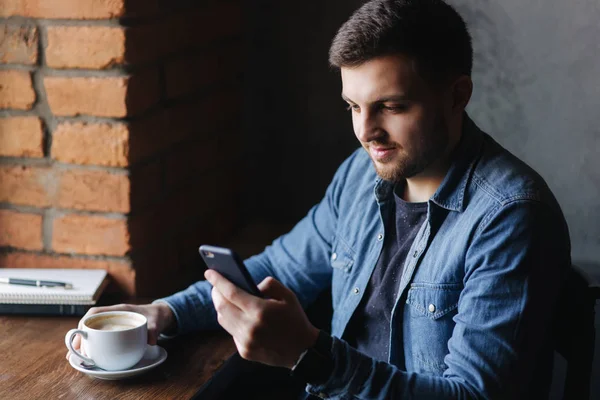 Ung affärsman att ta ett samtal i café medan han använder en bärbar dator — Stockfoto
