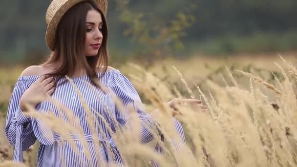 La mujer embarazada en la naturaleza se prueban el sombrero de punto. Antecedentes de campo y fachada blanca cerca de la granja. montañas — Vídeo de stock