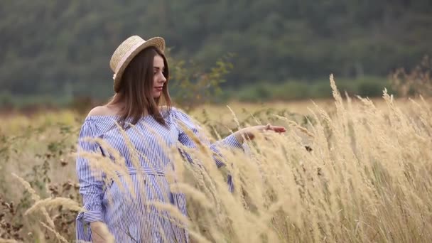 La mujer embarazada en la naturaleza se prueban el sombrero de punto. Antecedentes de campo y fachada blanca cerca de la granja. montañas — Vídeo de stock