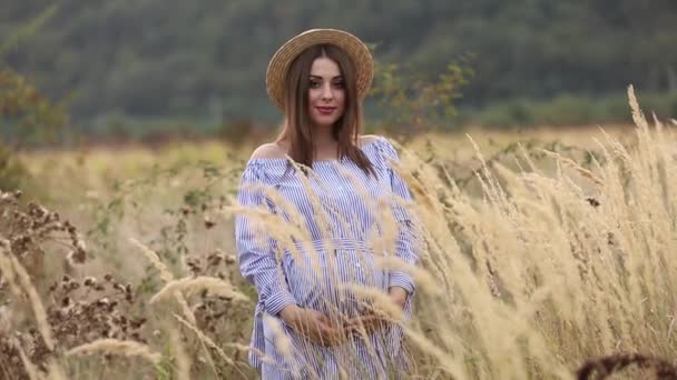 La mujer embarazada en la naturaleza se prueban el sombrero de punto. Antecedentes de campo y fachada blanca cerca de la granja. montañas — Vídeos de Stock