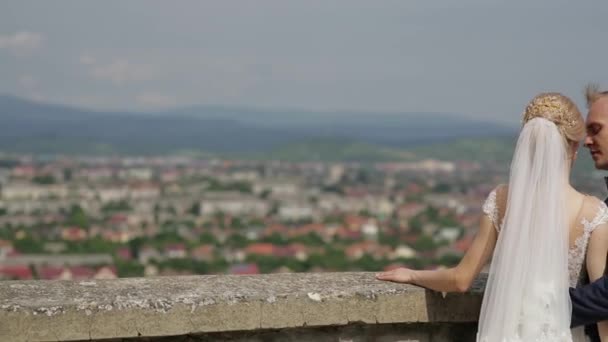 Hombre y mujer en la ropa de boda de pie en el castillo por la vista de la ciudad — Vídeos de Stock