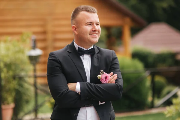 Porträt des jungen Bräutigams. Mann steht draußen im Garten. Hochzeitsanzug mit Fliege — Stockfoto