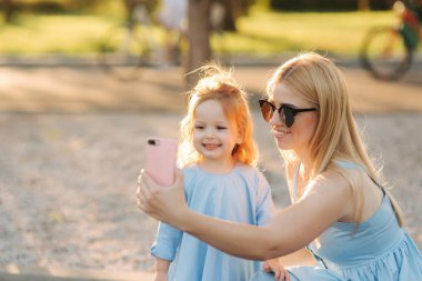 Anne ve küçük kızı parkta selfie olun