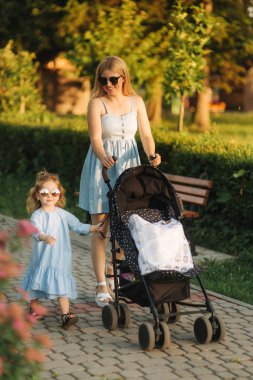 küçük kızı anne bebek arabası itme yardımcı olur. Mutlu bir aile