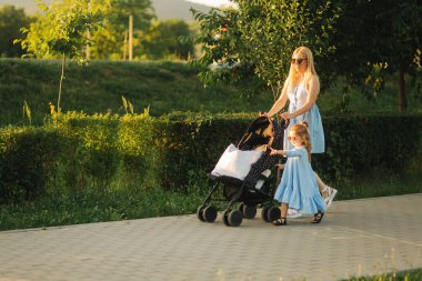 küçük kızı anne bebek arabası itme yardımcı olur. Mutlu bir aile