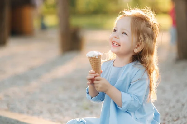 Szép kislány, egy kék ruhás eszik fagylaltot — Stock Fotó