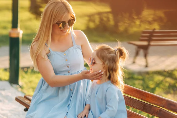 Moeder en zijn dochtertje zitten op een bankje in het park — Stockfoto