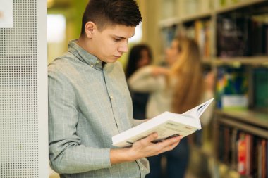 Kütüphanedeki erkek öğrenci bir kitap bulmak istiyor. Kitabı okudu. Heplful bilgi. Çalışma