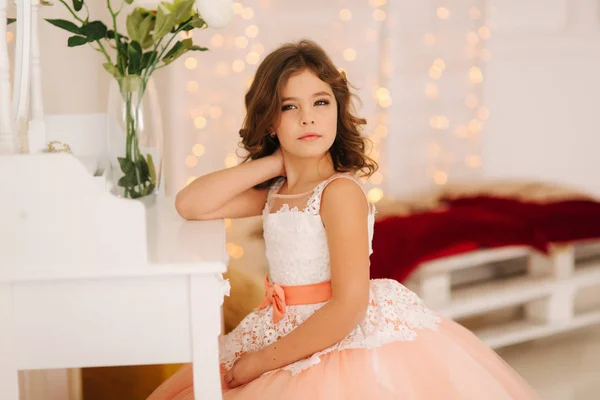 Kis lány ül a fehér zongora által. Fehér virágok, a zongorán. A gyönyörű ruha lány modell — Stock Fotó