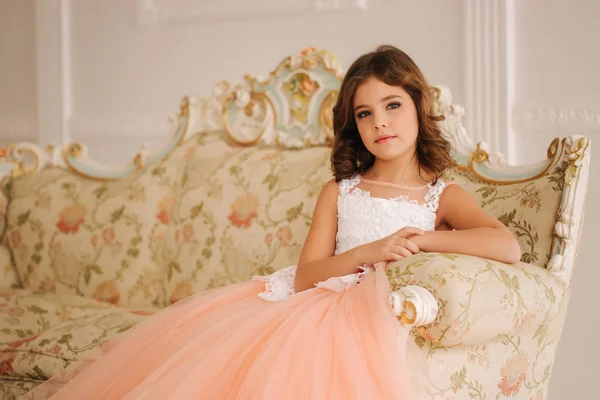 Portrait of little girl. Beautiful eyes of model. Little princess sit on a sofa — Stock Photo, Image