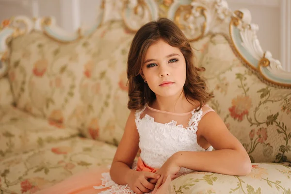 Πορτραίτο του μικρού κοριτσιού. Όμορφα μάτια του μοντέλου. Μικρή πριγκίπισσα κάθονται σε έναν καναπέ — Φωτογραφία Αρχείου