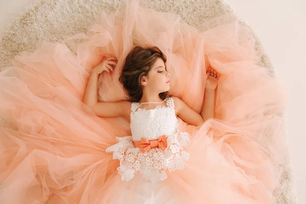 Photo of little girl in studio. Little beautiful girl with brown hair in a Peach-colored dress.