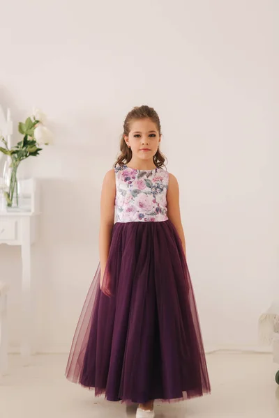 Glückliches Kind weiblich in lila Kleid. Schönes Make-up und Frisur — Stockfoto