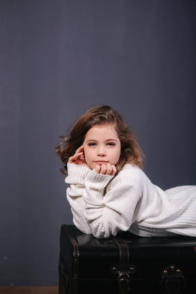 Niña hermosa con el pelo castaño en un suéter blanco. Estudio. Una princesa posa para un fotógrafo. Maquillaje y peinado — Foto de Stock