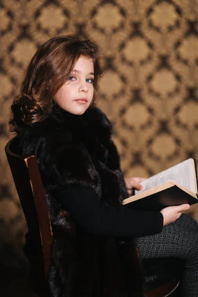 Hermosa niña está leyendo un libro en la biblioteca. Preparación para una escuela —  Fotos de Stock