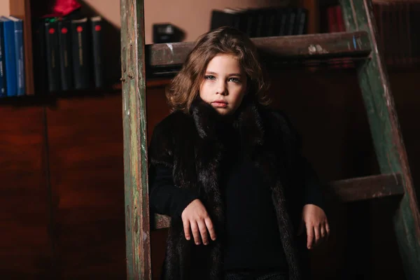 Niña parada junto a la escalera de la biblioteca. Libros —  Fotos de Stock