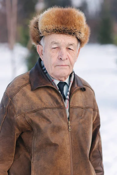 Vecchio col cappello invernale. Uomo anziano in walkink nel parco — Foto Stock