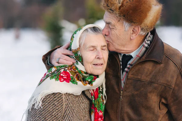 Portrait of senior couple. Elderly man kiss his wife in weighty. old couple walkink in the park in winter time. Happy family. Gold wedding