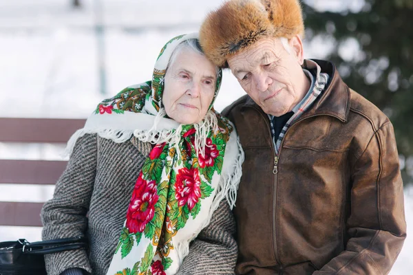 老人坐在公园里的本克上。幸福的老年夫妇在冬天呆在外面 — 图库照片