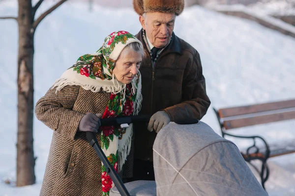 Grand Grandparents walking with a baby in beautiful pram. Winter time — Stock Photo, Image