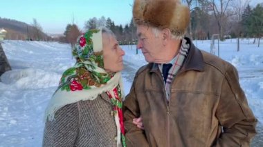 Parkta yaşlı çift kış döneminde rahatlatıcı. Mutlu Büyükbaba ve Büyükanne birlikte yürüme