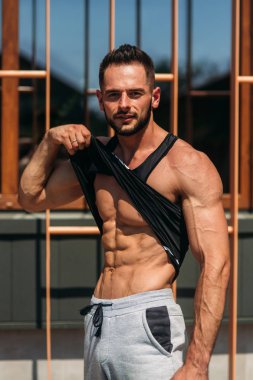 Genç bir atlet spor salonunda eğitiyor. Adbominal kasları gösterir. Dışarıda