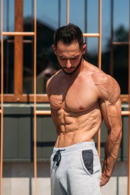 Genç atlet ile bir gövde bir tuğla duvar arka plan fotoğraf için poz. Kurtarma vücut geliştirmeci, atlet pompalanır kaslar, göğüs ve kol ile