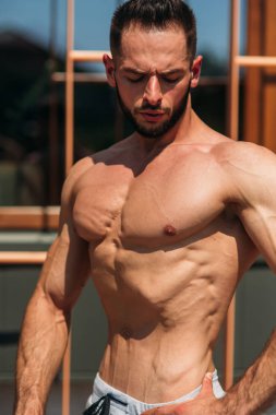 Genç atlet ile bir gövde bir tuğla duvar arka plan fotoğraf için poz. Kurtarma vücut geliştirmeci, atlet pompalanır kaslar, göğüs ve kol ile